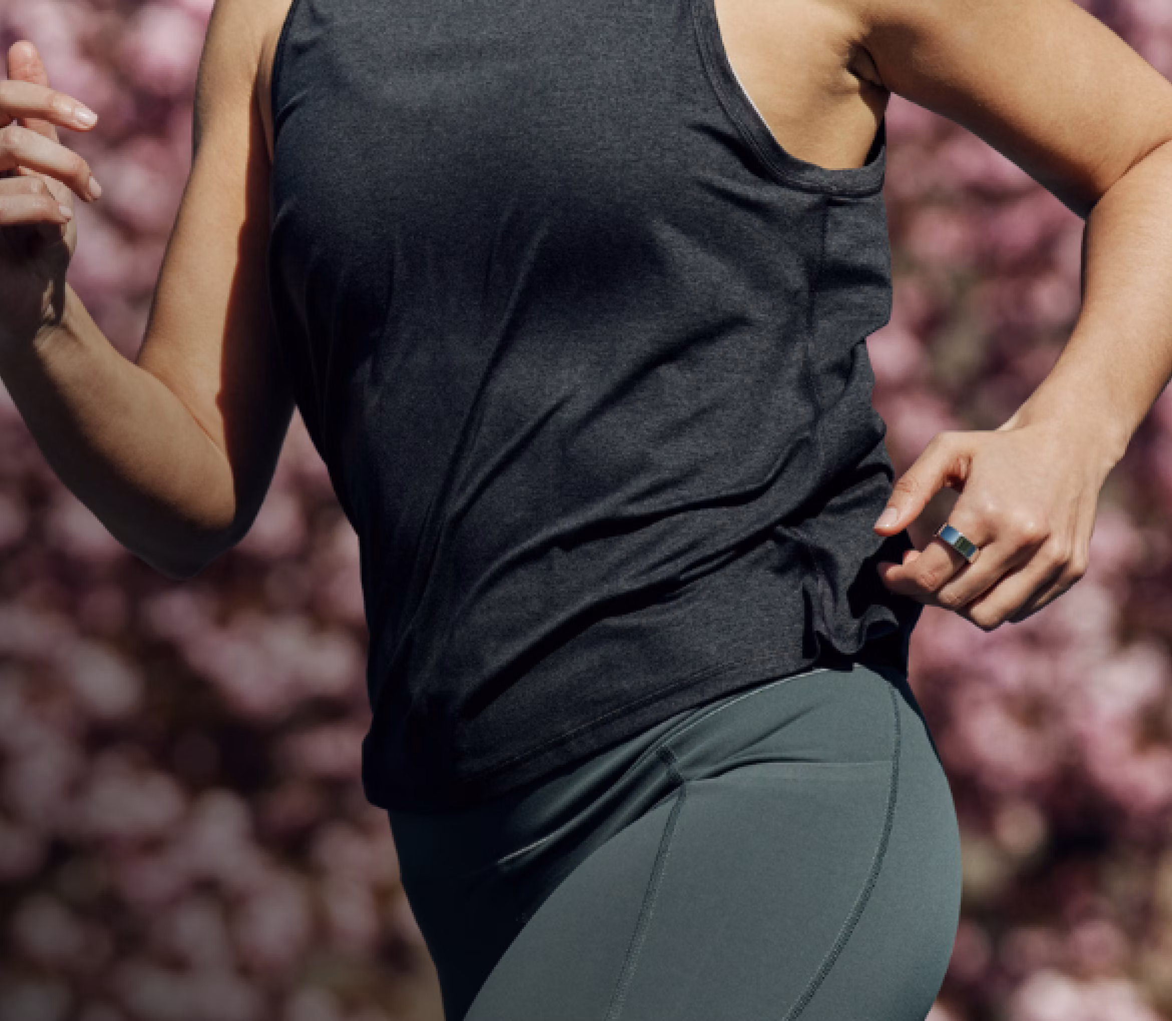 A woman in a jogger position wearing an Oura ring on her index finger.
